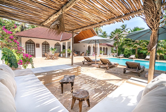 Pool terrace from under thatched canopy with garden views